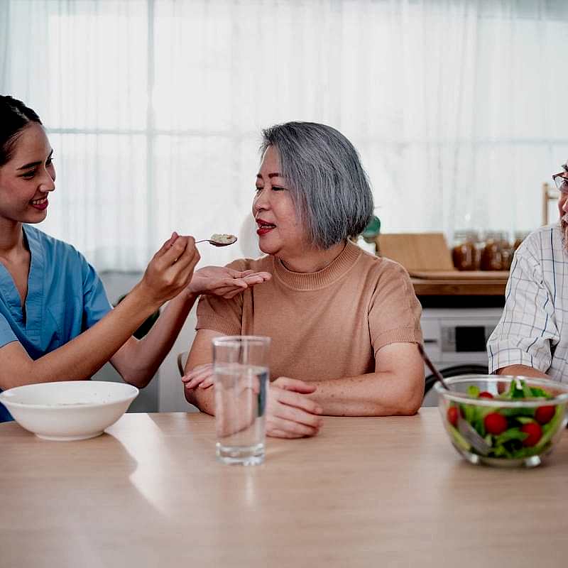 nurse-or-doctor-who-work-as-homecare-staff-help-to-serve-a-spoon-of-mush-rice-to-senior-woman.jpg